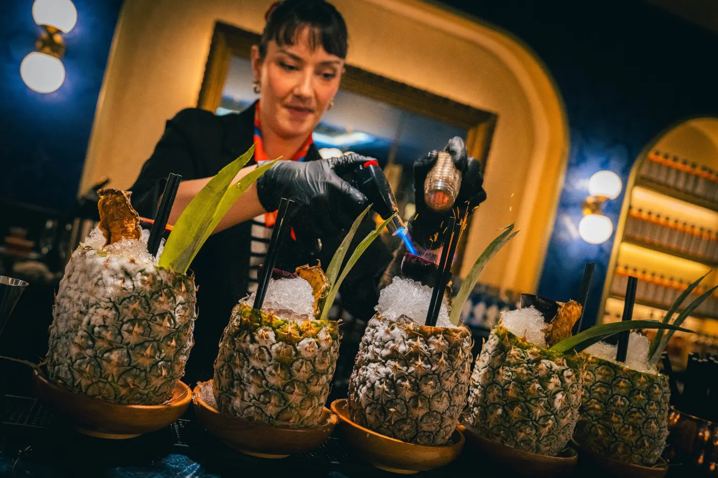 Bartender qui flambe des cocktails servis dans des ananas