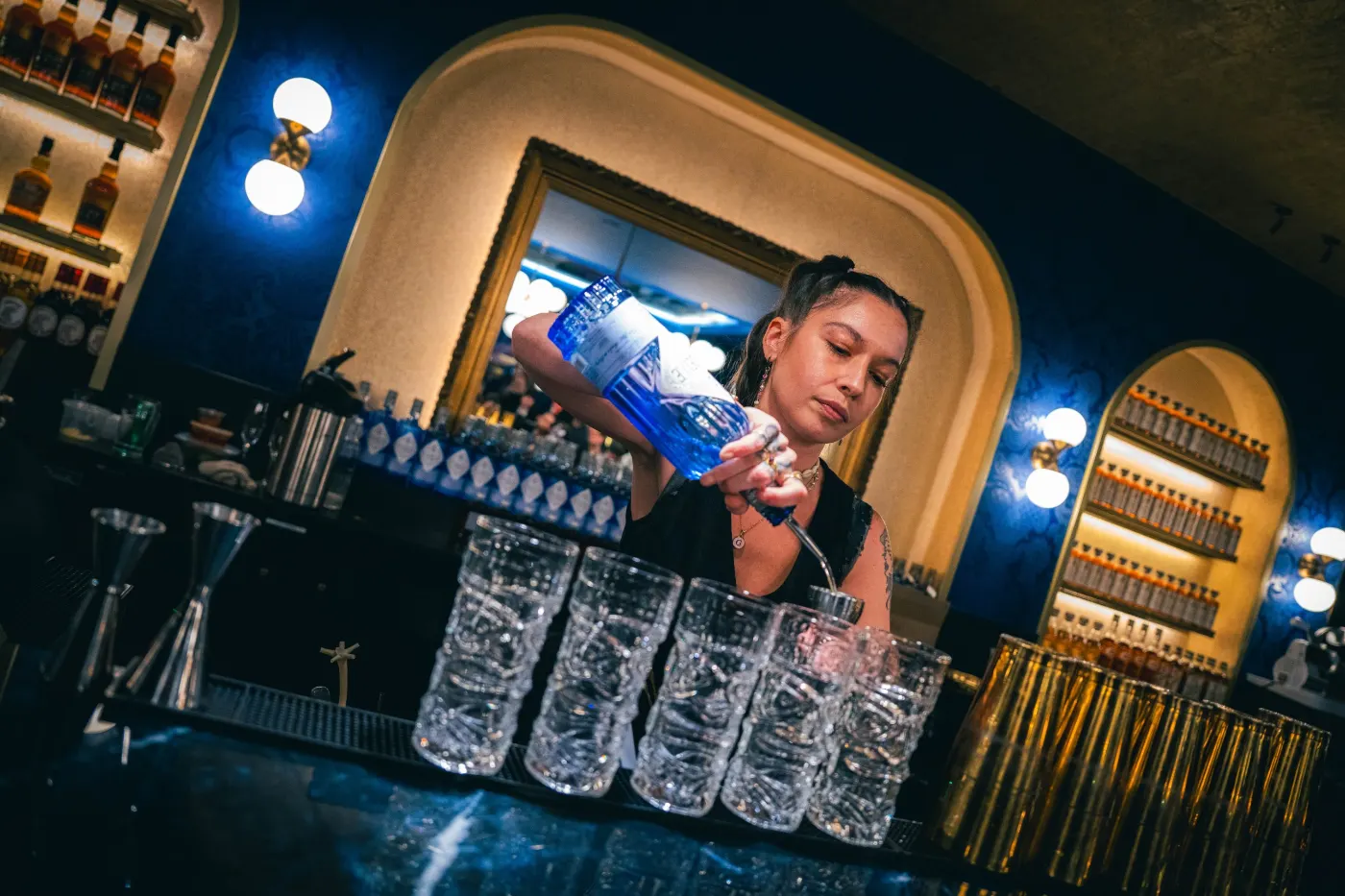 Bartender qui verse du gin au-dessus de verres en cristal