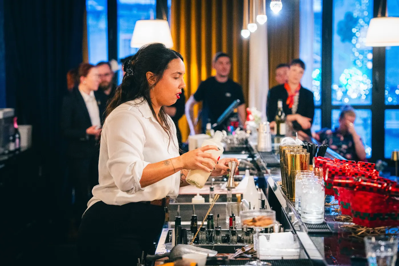Bartender en chemise blanche qui prépare son cocktail devant le public