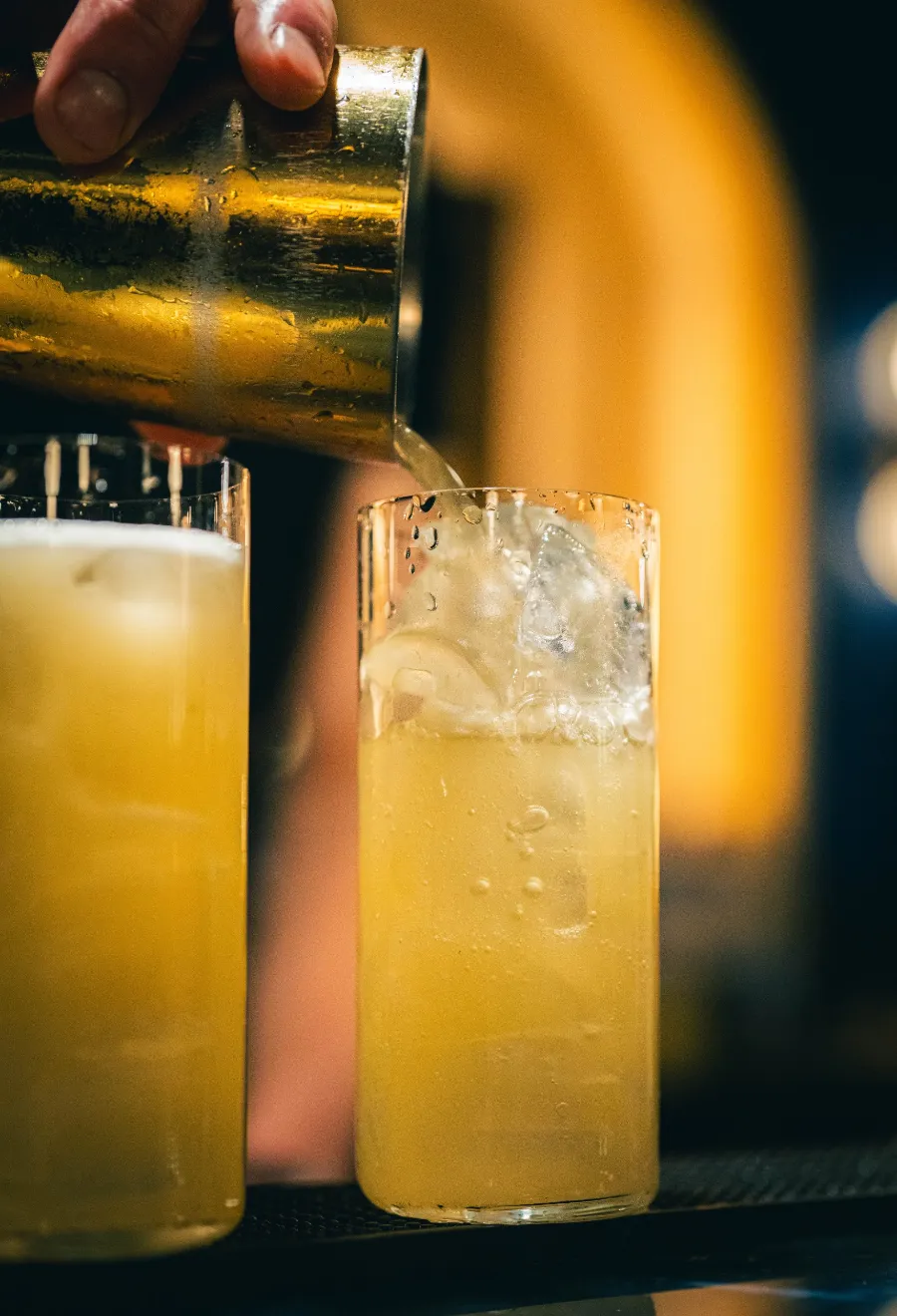 Bartender qui verse un cocktail dans un verre highball